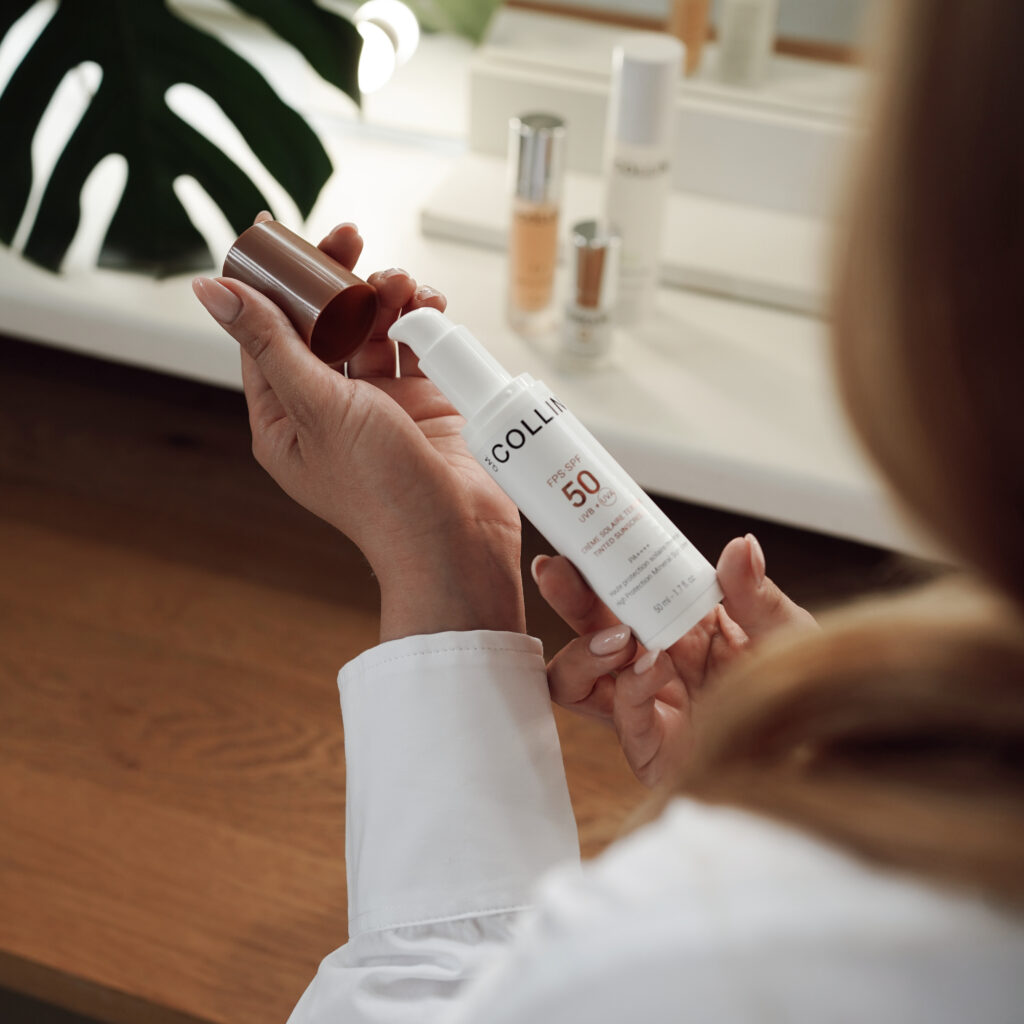 Light protection cream SPF 50 with Tinted Sunscreen pigment coloring, capacity of 50 ml in palms against the background of plants